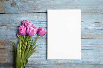 Blank white canvas mockup with flowers on wood background. Clean white canvas on rustic blue wal