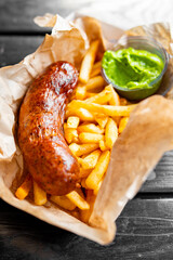 French fries, sausage and sauce on table. street food