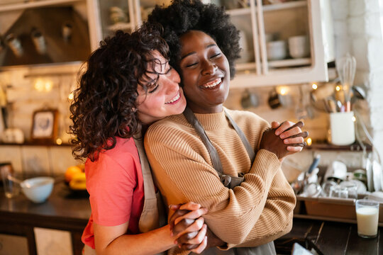 Authentic shot of happy married homosexual female gay couple laughing and embracing, lgbtq concept.