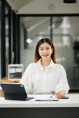 Obraz premium Successful Asian Businesswoman Analyzing Finance on Tablet and Laptop at modern Office Desk tax, report, accounting, statistics, and analytical research concept.