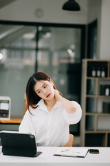 Fototapeta premium Overworked young Asian businesswoman office worker suffering from neck pain after had a long day at her office. office syndrome concept