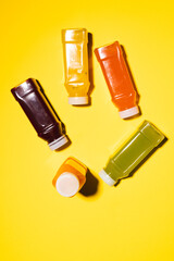 Close up of plastic bottles with fresh juice and copy space on yellow background