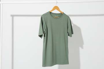 Obraz premium Green t shirt on hanger hanging from clothes rail with copy space on white background