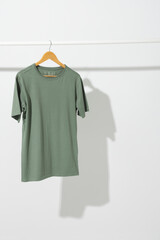 Naklejka premium Green t shirt on hanger hanging from clothes rail with copy space on white background