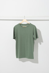 Fototapeta premium Green t shirt on hanger hanging from clothes rail with copy space on white background