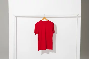 Zelfklevend Fotobehang Red t shirt on hanger hanging from clothes rail with copy space on white background © vectorfusionart