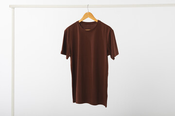 Obraz premium Brown t shirt on hanger hanging from clothes rail with copy space on white background