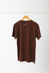 Naklejka premium Brown t shirt on hanger hanging from clothes rail with copy space on white background