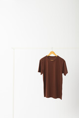 Naklejka premium Brown t shirt on hanger hanging from clothes rail with copy space on white background