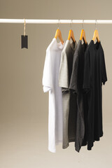 Obraz premium Four t shirts on hangers hanging from clothes rail and copy space on grey background