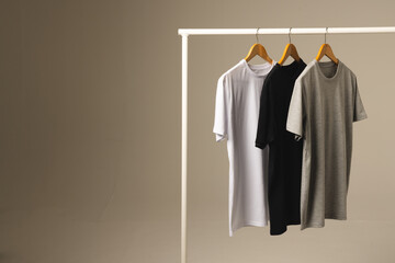 Naklejka premium Three t shirts on hangers hanging from clothes rail and copy space on grey background