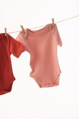 Two baby grows hanging from clothes line with pegs and copy space on white background