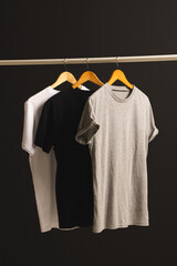 Obraz premium Three t shirts on hangers hanging from clothes rail and copy space on black background