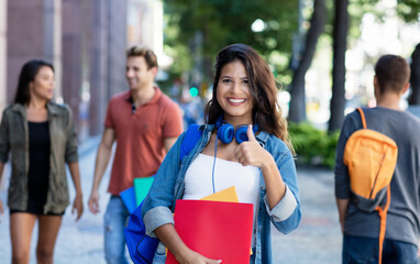 Pretty caucasian young adult woman walking in city with group of students