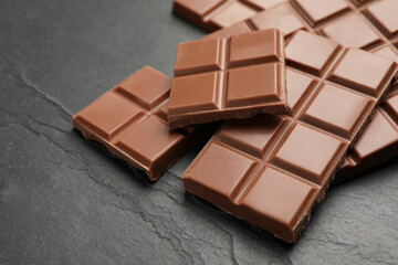 Delicious milk chocolate on black table, closeup