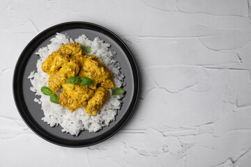 Delicious rice and chicken with curry sauce on white textured table, top view. Space for text