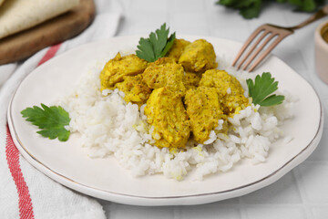 Delicious rice and chicken with curry sauce on white tiled table, closeup