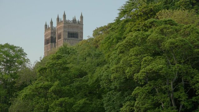 Long clip of the towers of Durham Cathedral framed by trees on a beautiful spring evening. 