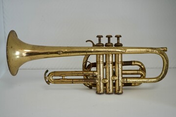 Gold Coloured Vintage Antique French Trumpet with white background.