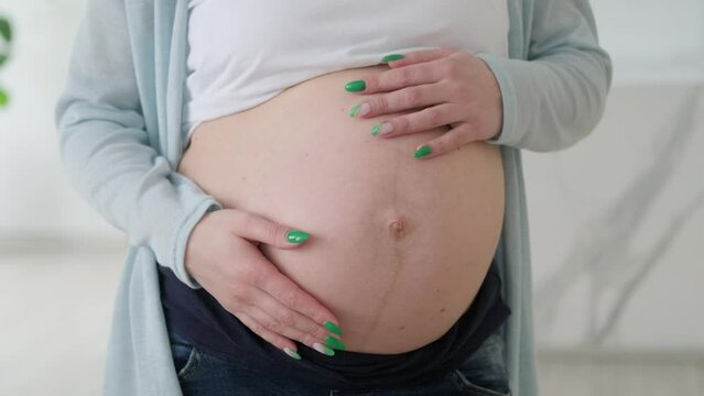 4k Pregnant expectant mother caressing her belly. Woman hands touching her tummy, waiting child. Preparation for childbirth, Girl big belly advanced pregnancy
