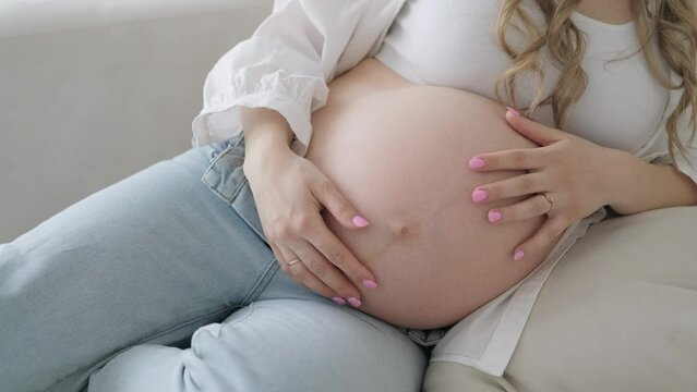 4k Pregnant expectant mother caressing her belly. Woman hands touching her tummy, waiting child. Preparation for childbirth, Girl big belly advanced pregnancy