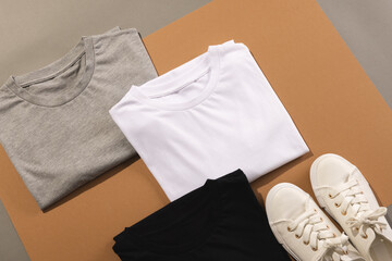 Close up of folded t shirts and white sneakers and copy space on brown background