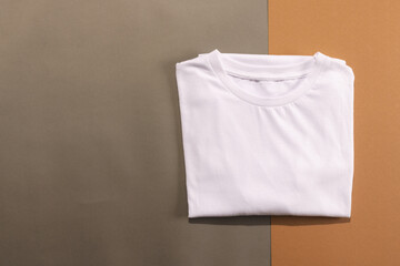 Close up of folded white t shirts and copy space on brown background