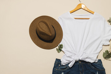 Flat lay of white t shirt, sunhat and denim shorts with copy space on cream background