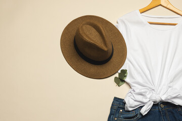 Flat lay of white t shirt, sunhat and denim skirt with copy space on cream background
