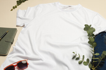 Flat lay of white t shirt, sunglasses and denim trousers with copy space on cream background