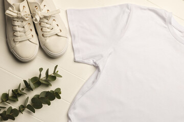 Close up of flat lay of white t shirt, sneakers, leaves and copy space on white boards background