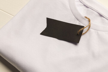 Close up of flat lay of white t shirt with tag and copy space on white boards background