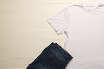 Close up of flat lay of white t shirt, denim trousers and copy space on white boards background
