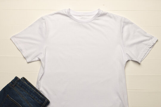 Close up of flat lay of white t shirt, denim trousers and copy space on white boards background