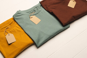Close up of flat lay of three t shirts with tags and copy space on white boards background