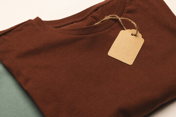 Close up of flat lay of brown t shirt with tag and copy space on white boards background