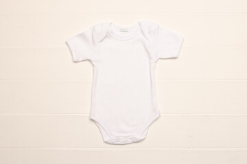 Flat lay of white baby grow with copy space on white board background