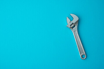 Chrome adjustable wrench on blue background copy space. Maintenance, repair, industry, manufacture...