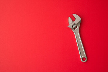 Chrome adjustable wrench on red background copy space. Maintenance, repair, industry, manufacture...