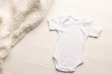 Flat lay of white baby grow and fur rug with copy space on white board background