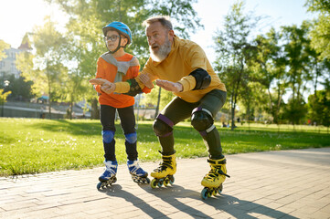 Little boy teaching his father riding roller skates in park