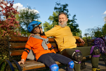 Happy grandparent and grandchild rest on bench after racing on roller skates