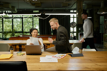 Business people using gadgets talking and smiling during meeting in office
