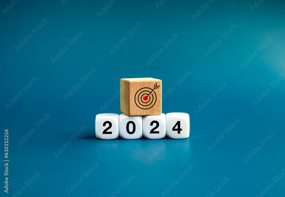 Wall mural The calendar year 2024 with goal and success concept. Target icon on wooden cube on white blocks with 2024, new year number, isolated on blue background. Happy new year, big business goals banner.