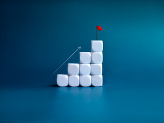 Arrow rising up to the flag on the top of white blocks as a business graph steps isolated on blue...