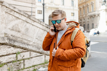 Happy young man with smartphone calling on city street. Technology, communication and people...
