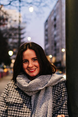 Woman in winter clothes smiling at camera outdoors at night