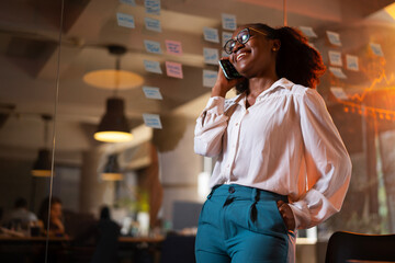 Happy businesswoman in office. Portrait of beautiful businesswoman using the phone. Woman talking to the phone.