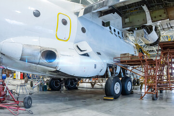 White transport airplane in the hangar. Aircraft under maintenance. Checking mechanical systems for flight operations