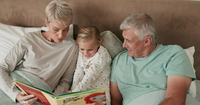 Bed, book and grandparents reading to a grandchild while in their home to relax together at a sleepover. Love, children and storytelling with a girl in the bedroom, bonding with granny and grandpa